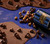 View of a Petite Signature Blue tin spilled over with Hot Cocoa CaramelCrisp Mix falling out on a table surface with melted chocolate in the foreground and background